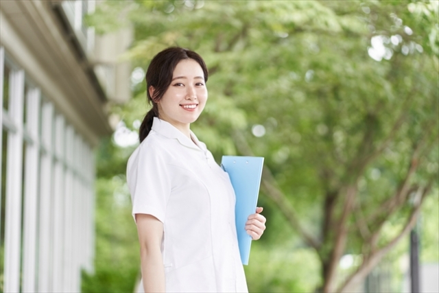 看護学生の制服を着た女性が屋外で微笑んでいる様子