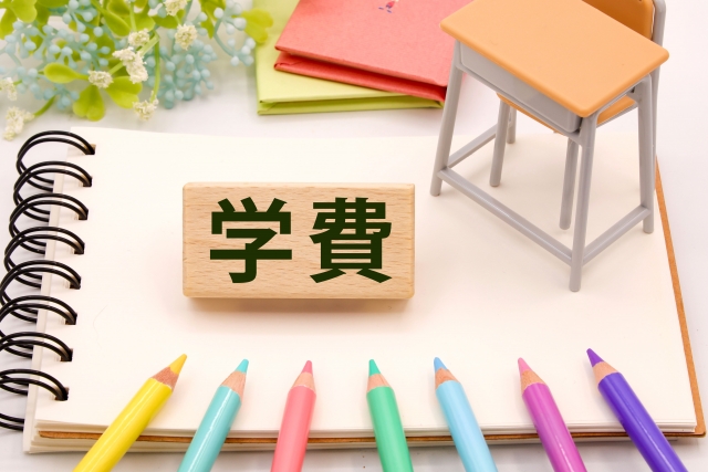 学費の文字が書かれた木札と色鉛筆、入学準備のイメージ