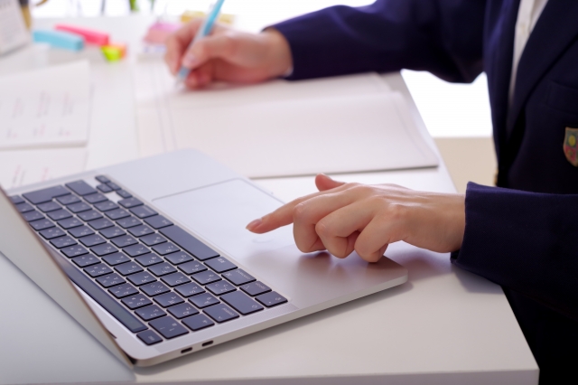 母子家庭で通信制高校に通う高校生がノートを取りながらノートパソコンで学習している様子。自宅学習やレポート提出を行う通信制高校のリアルな勉強風景。