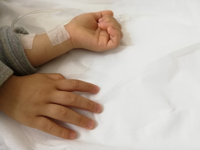 点滴を受けている子どもの手。母子家庭が医療費助成を利用する場面をイメージした写真