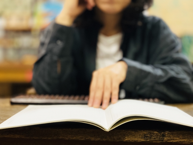 フリースクールの利用や子どもの学習について悩む母子家庭のお母さんが、ノートを開いて検討している様子